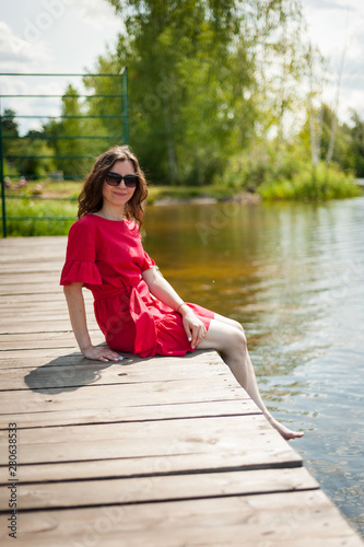 Beautiful brunette in a red dress walking in a Sunny Park © Evgeny Leontiev