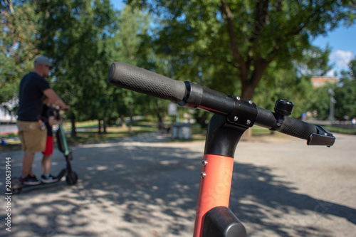 A man with a children riding an electric scooter on a sunny summer day.