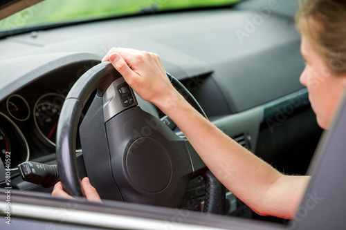 Car interior. Dashboard and woman hands on steering wheel driving a car. © bilanol
