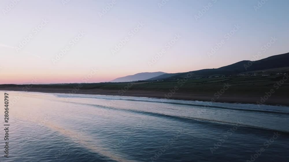Drone flying over the water during sunset with mountains in background. Drone flying over the water during sunset with mountains in background.