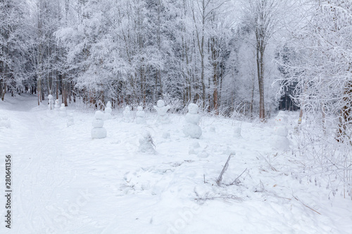 Winter scene in a rest zone near a forest. Benches and snowmen, forest road © edojob