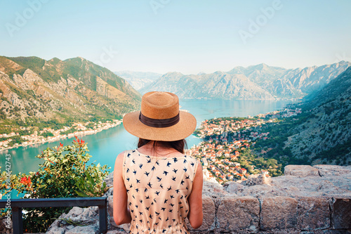 Rear view of young woman in dress and hat, who looking from above to the Kotor city and Boka bay, Montenegro photo