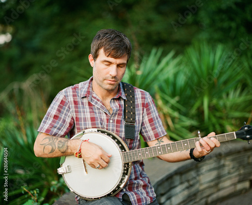 Handsome man playing banjo in a park