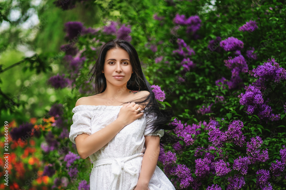 Spring portrait of stunning woman walking in the blooming lilac garden. Spring portrait of stunning woman walking in the blooming lilac garden.