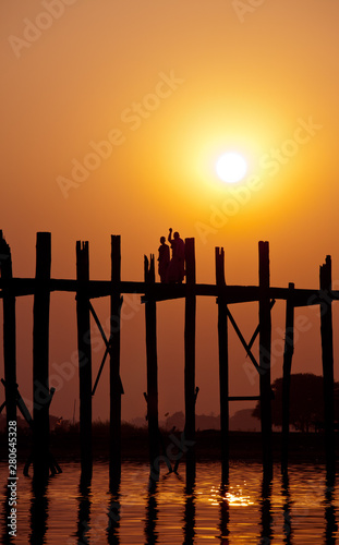 Silhouette of two bald monks on U Bein Bridge at sunset, Amarapura, Mandalay region, Myanmar. Burma. The longest and oldest teak wooden bridge in the world