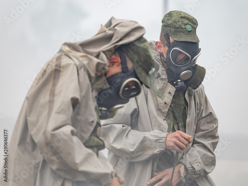 Soldiers in smoke wear chemical protection suits