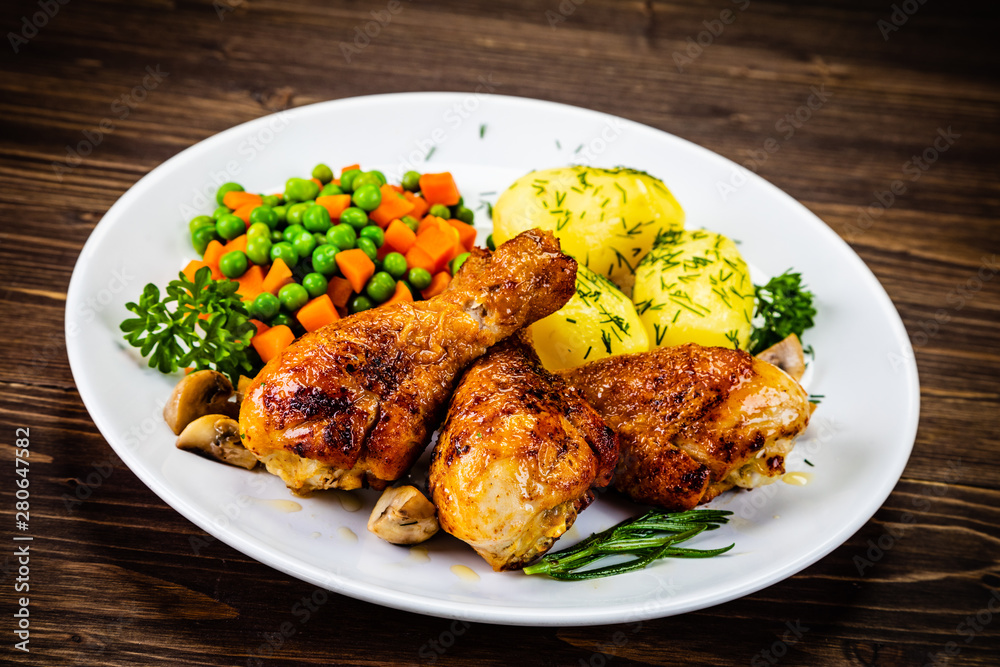 Grilled chicken drumsticks with vegetables on wooden background Grilled chicken drumsticks with vegetables on wooden background
