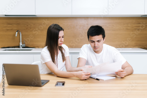 Stressed young couple checking bills at home