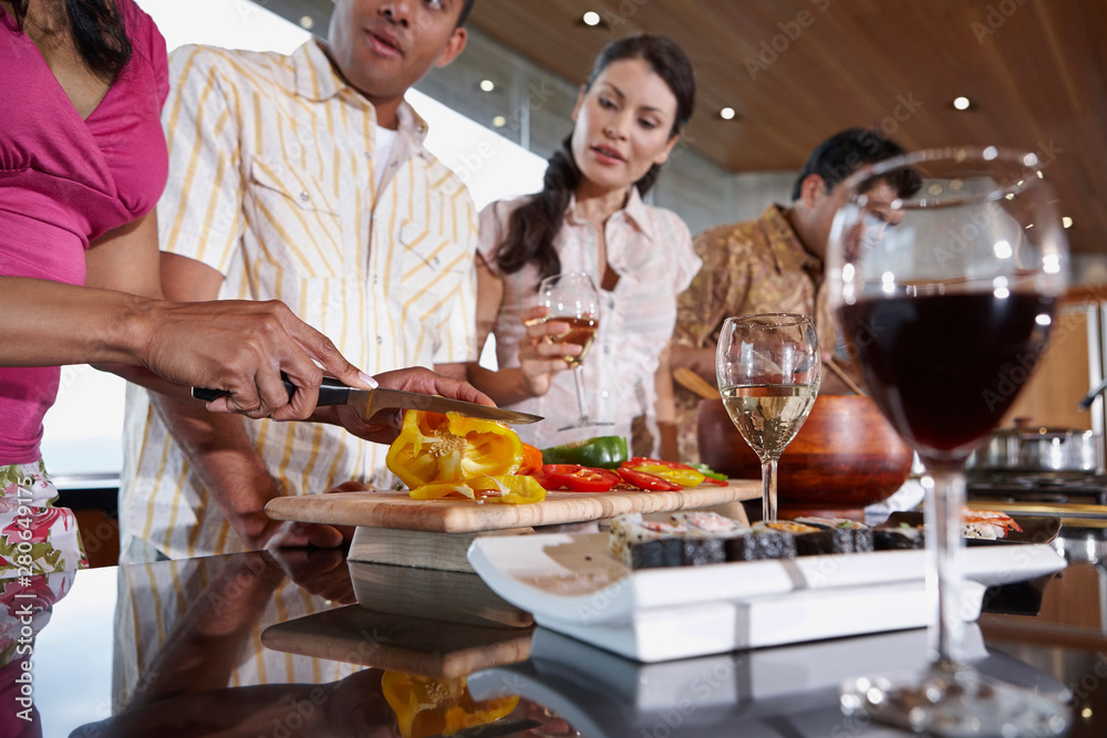 Group of multi-ethnic friends prepping for dinner party in the kitchen Group of multi-ethnic friends prepping for dinner party in the kitchen