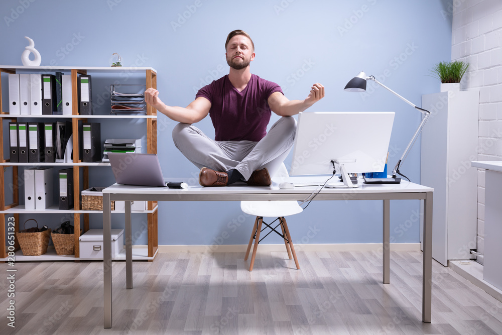 Businessman Meditating Over Desk - obrazy, fototapety, plakaty 
