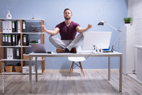 Foto Businessman Meditating Over Desk
