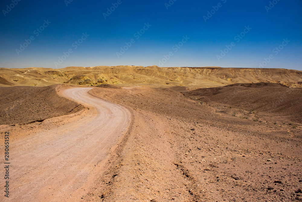 curved lonely trail in desert landscape wilderness natural environment with nothing around and bare sand stone mountain background 
