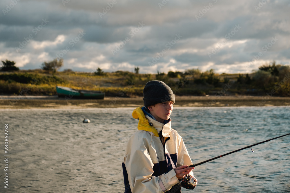 teenager with wooly hat fishing by seaport teenager with wooly hat fishing by seaport