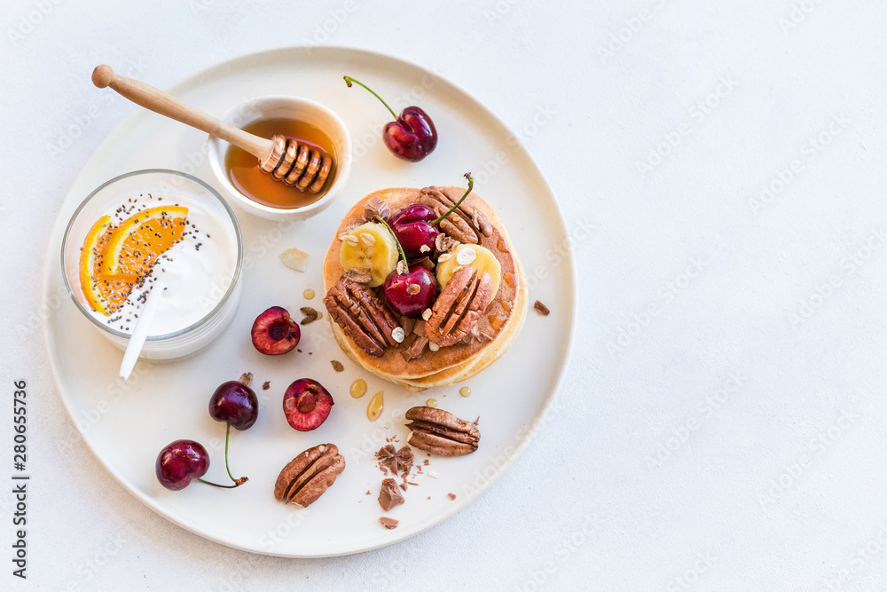 Breakfast concept. Pancakes with black cherries, bananas, pecans, yogurt and honey. Breakfast concept. Pancakes with black cherries, bananas, pecans, yogurt and honey.