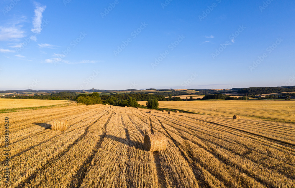 Gemähtes Getreide Feld mit Heuballen bei Sonnenuntergang