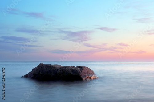 A stone in a calm sea at sunset