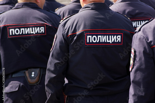 Russian police officers on patrol in the town square. View from the back. The inscription on the uniform: the police