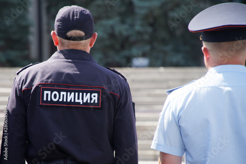 Two Russian policemen in different uniforms on patrol in the town square. View from the back. Problems of opposition rallies, detentions and arrests