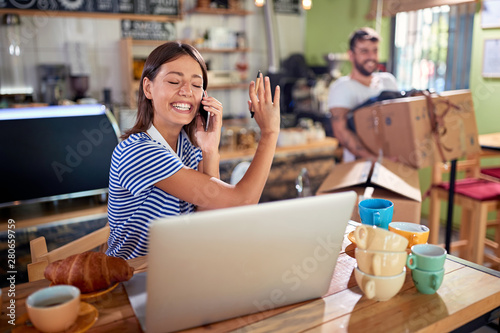 Woman owner working with laptop ready to open their cafe..