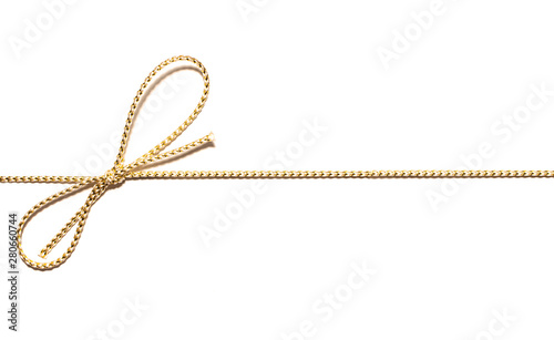 Golden satin rope parallel to frame with knotted bow gift ribbon wrap for Christmas present with intricate shine details isolated cut out top view on simple plain wide banner white background.