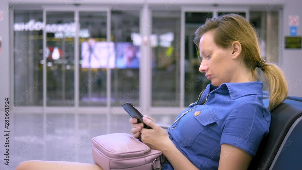 girl in airport waiting area using smartphone. travel concept girl in airport waiting area using smartphone. travel concept