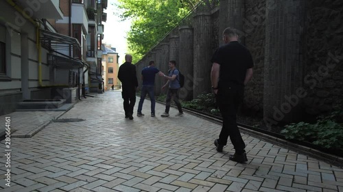 Young lonely male walking down alleyway fighting off muggers applying Krav Maga self defense techniques and running away. Group of robbers attacking man photo