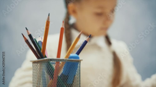 Schoolgirl is putting red pencil back into the basket.