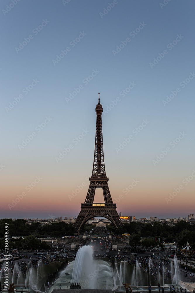 The Eiffel Tower at sundown featuring a fountain in the foreground. The Eiffel Tower is known as one of the main attractions of Paris.