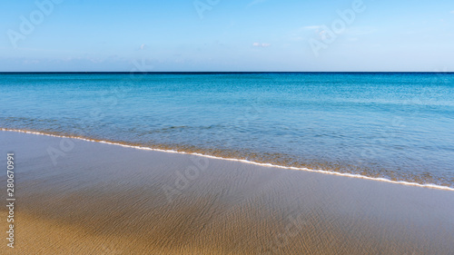 Tropical sandy beach with blue sky and wave crashing on sandy shore image for nature background or summer background