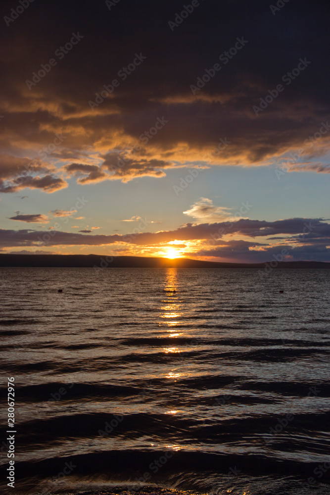 Obraz premium sunset, dramatic clouds, reflection of the sun in the water of the lake