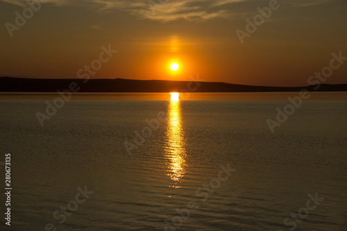 Beautiful golden orange sunset over the lake. The sun sets turning the sky yellow  orange   red tones   reflects in the lake.