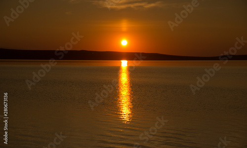 Beautiful golden orange sunset over the lake. The sun sets turning the sky yellow  orange   red tones   reflects in the lake.