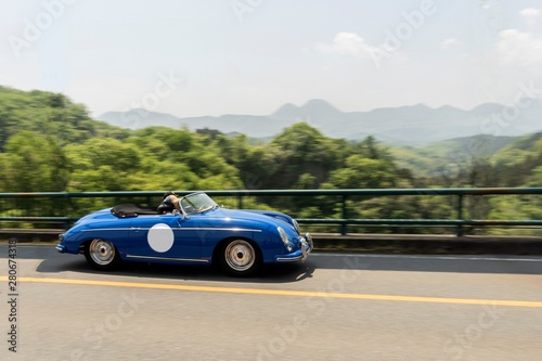 走行中の青いクラシックカー／景色がボケてスピード感がある © yumiko