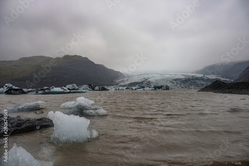 The Solheimajokull Glacier in Iceland showing icebergs and calved ice in the lagoon as ice calves and melts together with the erosion caused by the receding glacier
