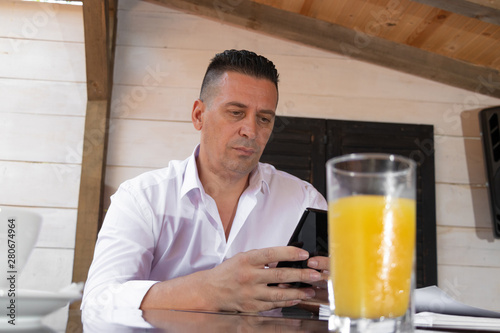 man drinking coffee in cafe and looking in mobile phone very concern