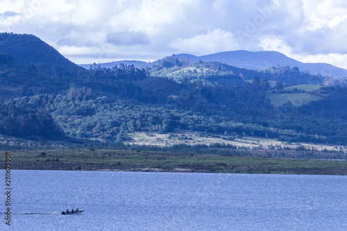 Small boat, with people watching the lagoon and the mountains of the landscape