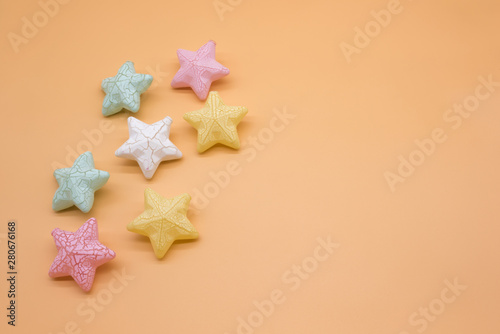 Beautiful colorful stars props placed on orange background creative top view, christmas decoration background