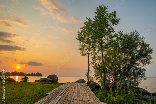 sunset at Franklin Beach Georgina Ontario Canada with nice trees  rocks  lake view  clouds  sun and wooden path
