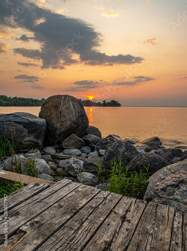 sunset at Franklin Beach Georgina Ontario Canada with nice trees, rocks, lake view, clouds, sun and wooden path