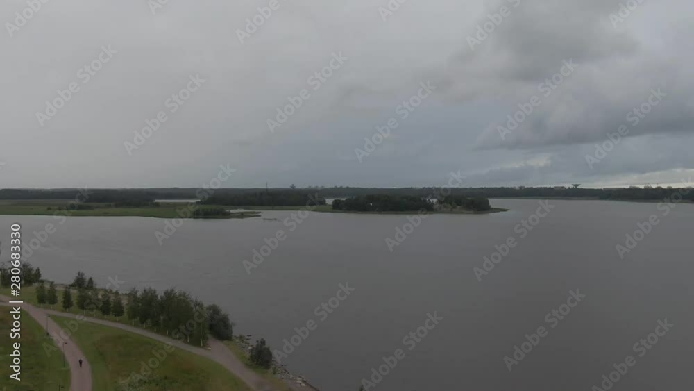 Flying over lake and park in the city. Arial drone shot. Water. Green grass. Flying over lake and park in the city. Arial drone shot. Water. Green grass.