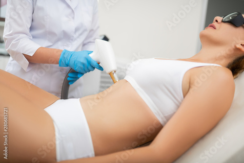 Woman getting laser belly skin treatment in a beauty salon.