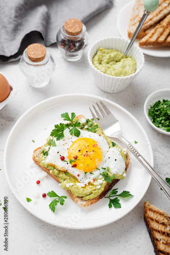 Toast with avocado puree and fried egg, healthy breakfast. 