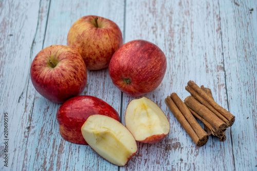Organic ripe apples and cinnamon sticks on a wooden table. Fresh cut apple. Cooking ingredients. Harvest.