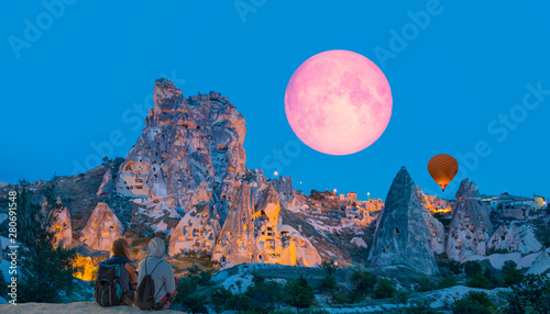 Amazing view of Uchisar castle in Cappadocia at twilight blue hour - Girls watching moonrise at the hill of Cappadocia"Elements of this image furnished by NASA" 