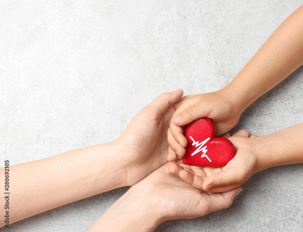 Woman and child holding heart on grey stone background, top view with space for text. Donation concept Woman and child holding heart on grey stone background, top view with space for text. Donation concept