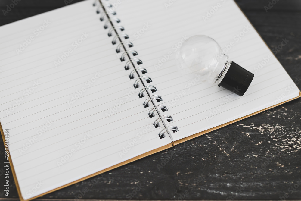 Plakat concept of brainstorming lightbulb on open empty notebook