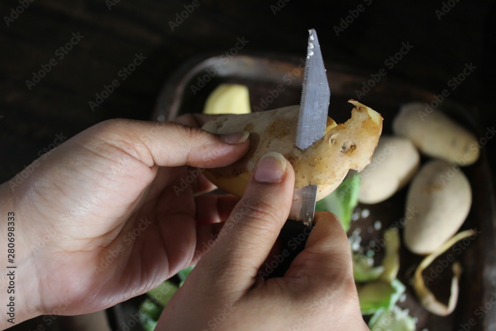 Closeup of female hands peeling potatoes