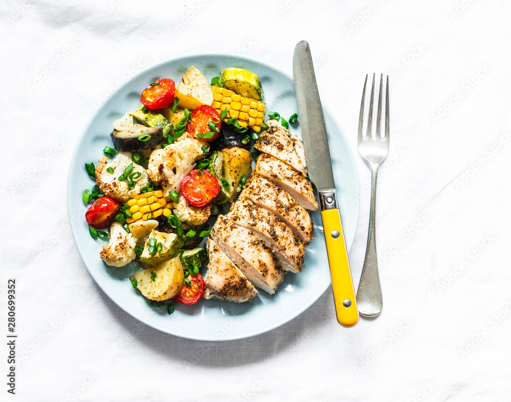 Chicken breast baked with potatoes, cauliflower, corn, eggplant, zucchini, cherry tomatoes on a light background, top view. Healthy food diet concept Chicken breast baked with potatoes, cauliflower, corn, eggplant, zucchini, cherry tomatoes on a light background, top view. Healthy food diet concept