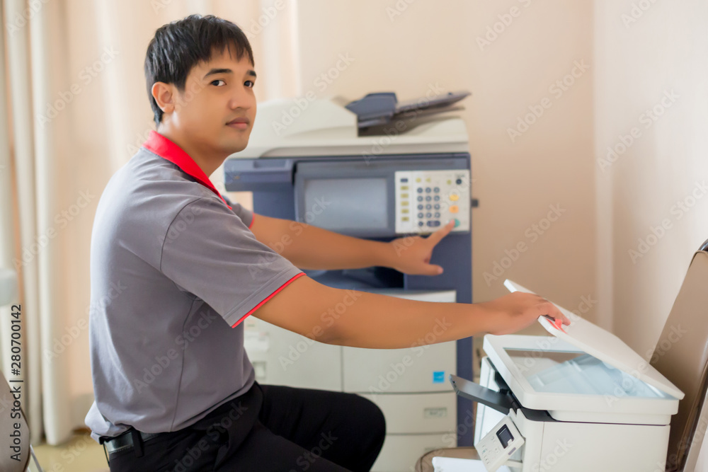 Selective focus to men press the button on panel of the copier and scanner. Business man using all in one machine, printer, scanner and copier. Working in office concept.