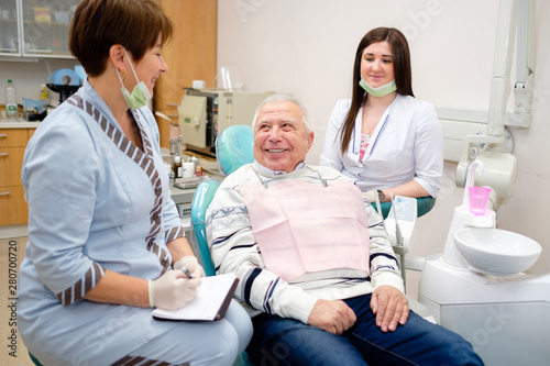 Portrait of senior man, doctor and nurse on the first dental visit at  dental office. Old senior patient 70 years old. Dentistry, medicine and health care concept.Group of people in dental clinic